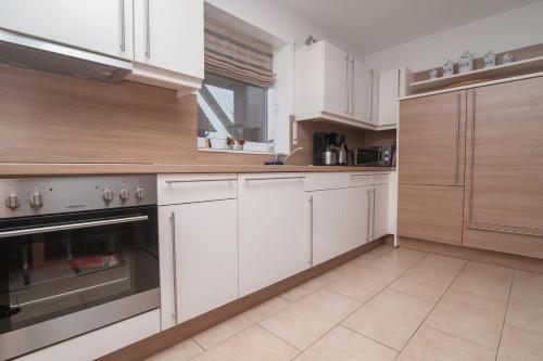 a kitchen with white cabinets and a stove top oven at Ferienhaus Carpe Diem in Greetsiel