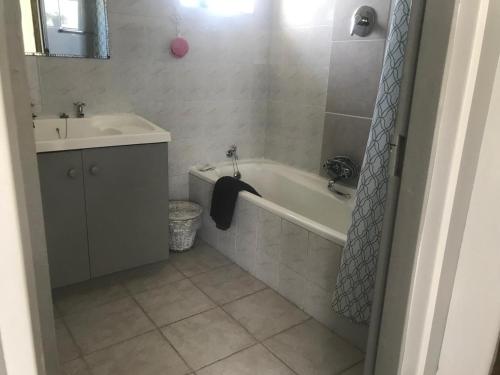 a bathroom with a bath tub and a sink at 120 steps to the beach in Pringle Bay