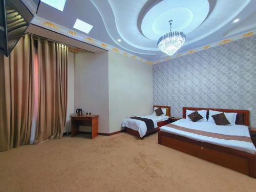 a bedroom with two beds and a chandelier at DREAM PLAZA HOTEL for your convenience in Bukhara