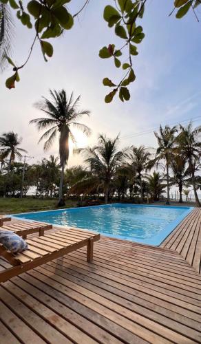 a swimming pool with a wooden deck and palm trees at Playa Mulata in Moñitos