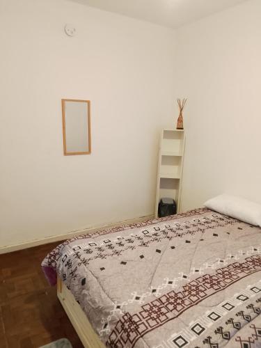 a bedroom with a bed and a picture on the wall at Hostel Küyen Mapu in Comodoro Rivadavia