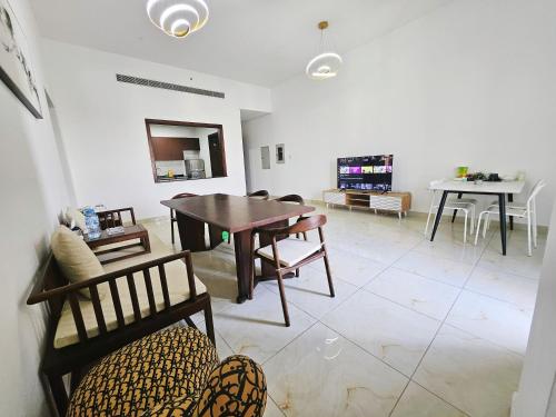 a living room with a table and chairs and a tv at Golden Homes 2 in Dubai