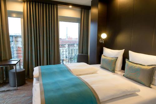 a large bed in a hotel room with a window at Motel One München-Olympia Gate in Munich