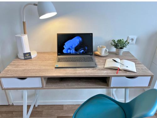 a laptop computer sitting on a desk with a book at Le Moment Douillet - Chambre privée in Bourbourg