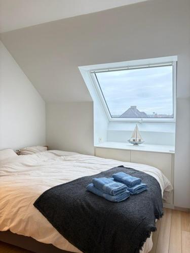 a bedroom with a bed with two blue towels on it at Maison Elouise in Middelkerke