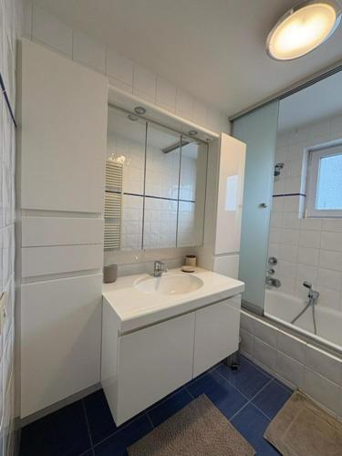a white bathroom with a sink and a mirror at Maison Elouise in Middelkerke