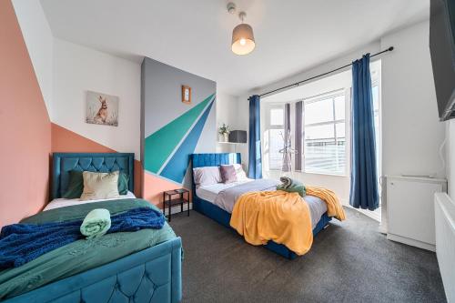 a bedroom with two beds and a large window at Six Bedroom Group Home near MediaCityUK with Garden and Lockbox Check In in Manchester