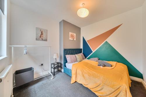a bedroom with a bed with an orange blanket at Six Bedroom Group Home near MediaCityUK with Garden and Lockbox Check In in Manchester