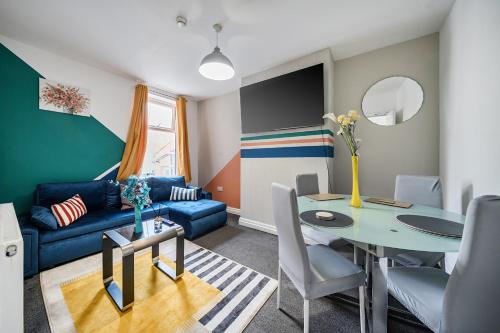 a living room with a blue couch and a table at Six Bedroom Group Home near MediaCityUK with Garden and Lockbox Check In in Manchester