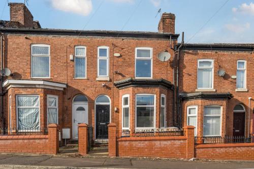 a red brick building with white windows and doors at Six Bedroom Group Home near MediaCityUK with Garden and Lockbox Check In in Manchester