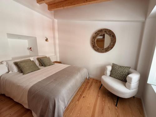 a bedroom with a bed and a chair and a mirror at Casa Da Muralha in Óbidos