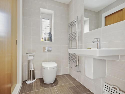 a white bathroom with a toilet and a sink at Knighton in Warmwell