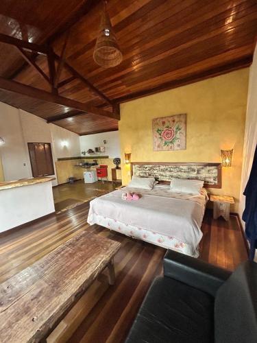 a large bedroom with a large bed and a bench at Chalés Lavras de Minas - Canadá in Lavras Novas
