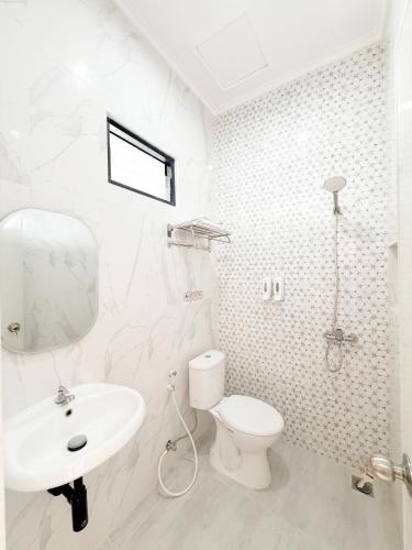 a white bathroom with a toilet and a sink at Aurora House Surabaya in Wijung