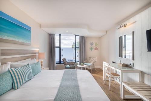 a hotel room with a large bed and a desk at Bayview Hotel in Plettenberg Bay