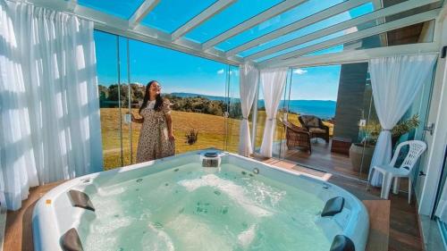 a woman standing in a jacuzzi tub in a house at Casa Paraíso do Sol - Rancho Queimado - SC in Rancho Queimado