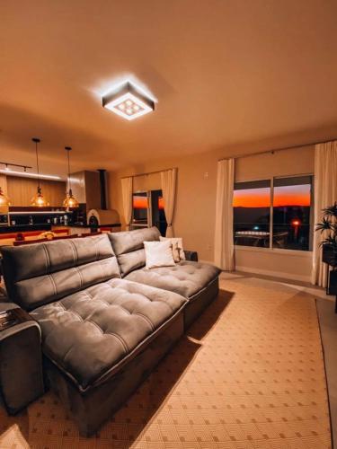 a large leather couch in a living room with a kitchen at Casa Paraíso do Sol - Rancho Queimado - SC in Rancho Queimado