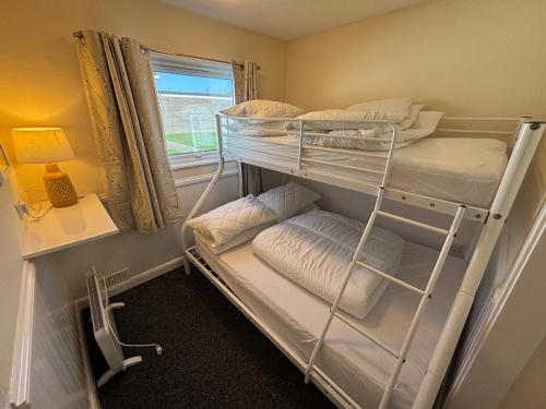a room with two bunk beds and a window at 116, Two bed Chalet on California Sands Holiday Park - Sleeps 5, pet friendly, includes FREE pool passes, Free Entry to Clubhouse - plus Electric, WiFi, bed linen and towels all included - only 300m from the beach! in Scratby