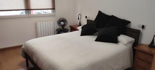 a bedroom with a white bed with black pillows at Sabino Arana 9, habitación doble con servicios compartidos in Lekeitio