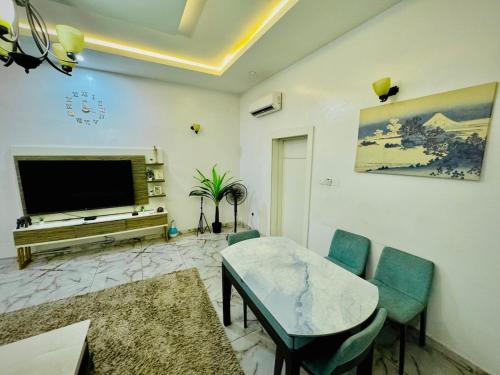 a living room with a television and a table and chairs at The Cape - Apartment in Bamgbose