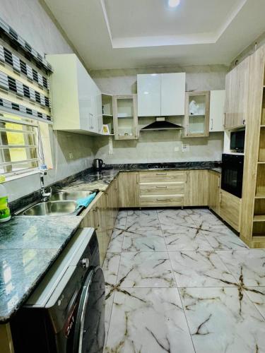 a kitchen with white cabinets and a marble floor at The Cape - Apartment in Bamgbose