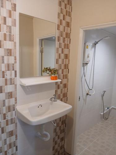 a bathroom with a sink and a shower with a mirror at บ้านในสวนรีสอร์ทBannnaisuan Resort in Prachuap Khiri Khan