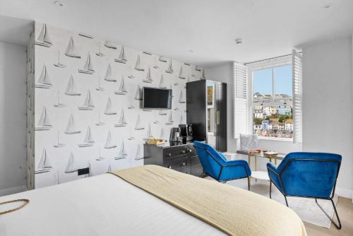a bedroom with a bed and two blue chairs at Golden Vanity Suite - Sea View - Free Wi-Fi in Brixham