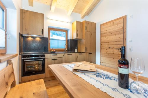 a kitchen with a wooden table with a bottle of wine at Hauserhof- Urlaub am Bauernhof inklusive Sommercard in Bramberg am Wildkogel