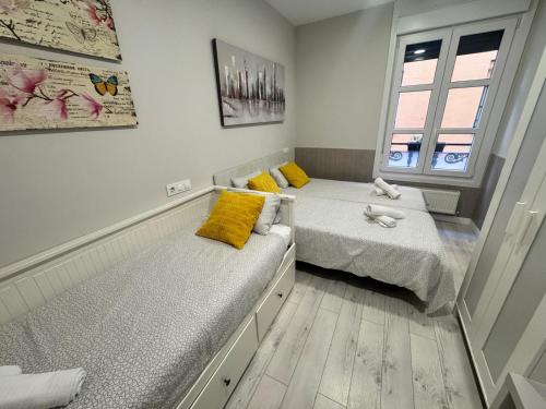 a bedroom with two beds with yellow pillows at Apartamentos Logroño Centro in Logroño