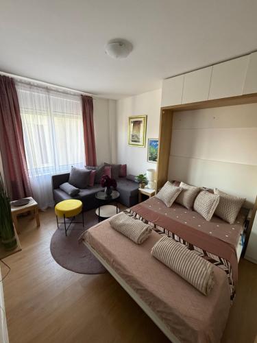 a bedroom with a large bed and a couch at Moderan Studio na Trgu Republike - Centar in Podgorica