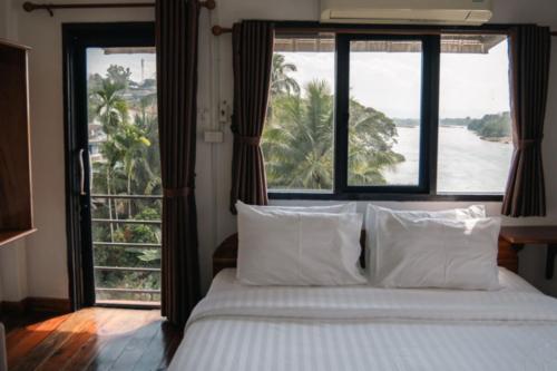 a bedroom with a bed with a view of the ocean at Riverside Houayxay Hotel in Ban Houayxay