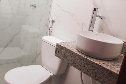 a bathroom with a toilet and a sink on a counter at Pousada Porto Maresias in Cabo Frio