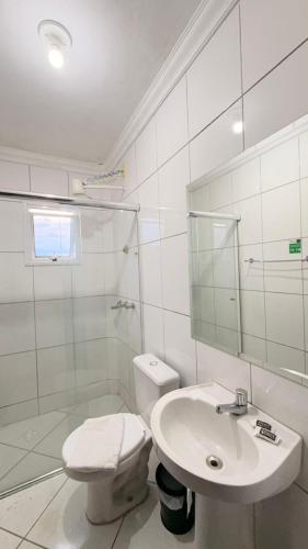 a white bathroom with a toilet and a sink at Imbau Palace Hotel in Imbau