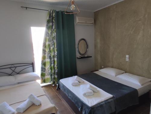 una camera d'albergo con due letti e uno specchio di El Mar Studios a Keramotí