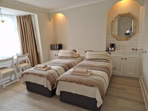 a bedroom with two beds and a mirror at Osterley Room in Isleworth