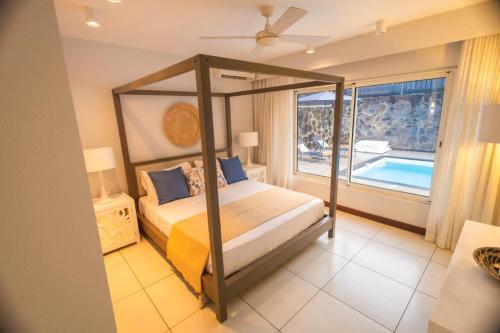 a bedroom with a canopy bed and a swimming pool at Seascape Villa in Pointe aux Biches