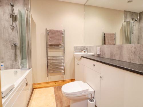 a white bathroom with a toilet and a sink at Old Sorting Office in Cheltenham