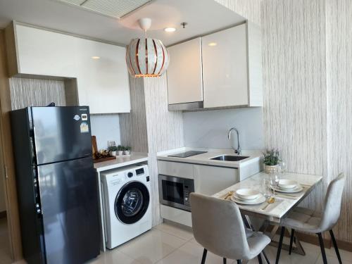 a kitchen with a refrigerator and a table with chairs at 1 BR 5mins to beach Sea view Riviera Wongamat in North Pattaya