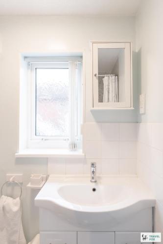 a white bathroom with a sink and a window at Birchenfield Holiday Cottages in Dilhorne