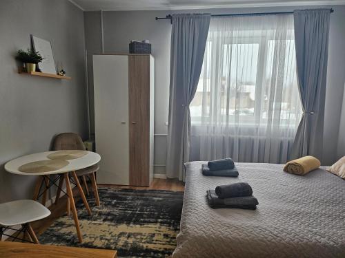 a bedroom with a bed and a table and a window at Studio apartment in Rēzekne