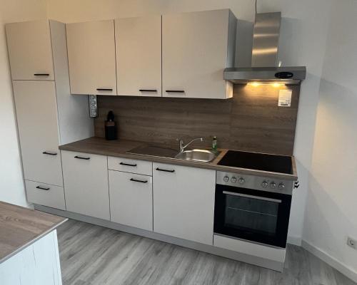 a kitchen with white cabinets and a sink and a stove at LT35a Haus Sternengucker in Dorum-Neufeld
