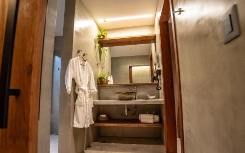 a bathroom with a sink and a robe on a shelf at Hotel Pontal de Ubu in Anchieta