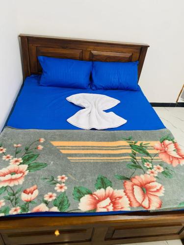 a bed with a blue comforter with flowers on it at Three D Rooms in Haldummulla