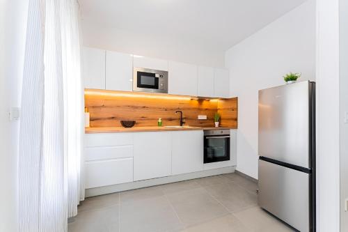a kitchen with white cabinets and a stainless steel refrigerator at Flex SelfCheckIns 99 - 2 Bedrooms - Parking - Loggia in Velika Mlaka
