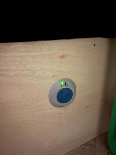 a switch on a wooden wall with a green light at napNQ in Manchester