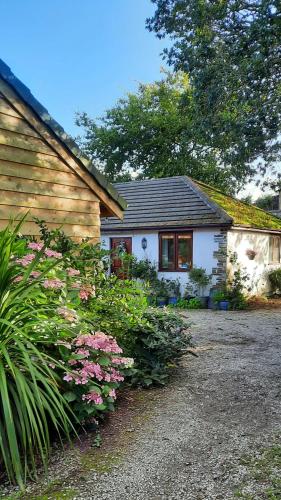 a small white house with flowers in front of it at The Studio with Terrace and EV point in Callington