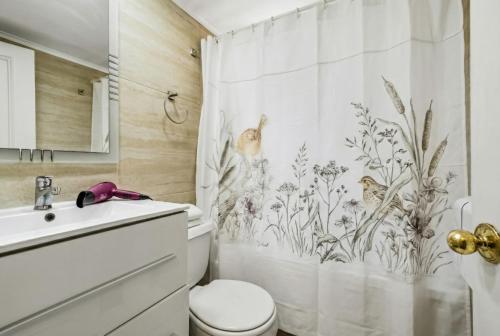 a bathroom with a shower curtain with birds and flowers at Isabel Suites Vitacura in Santiago