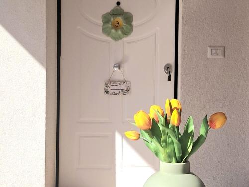a vase with yellow tulips in front of a door at La Rosa Verde in Castrovillari