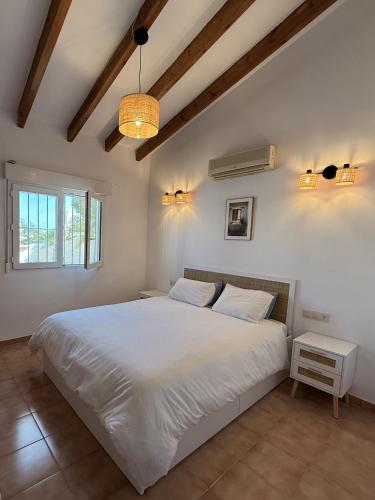 a bedroom with a large white bed and a window at Villa Cala Lanuza in Alicante