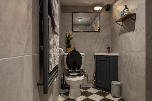 a small bathroom with a toilet with a black lid at 2 The Old Canteen, Two Minute Walk To Beach in Lyme Regis